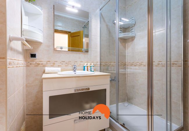 Casa de banho com chuveiro, lavatório com armário e espelho