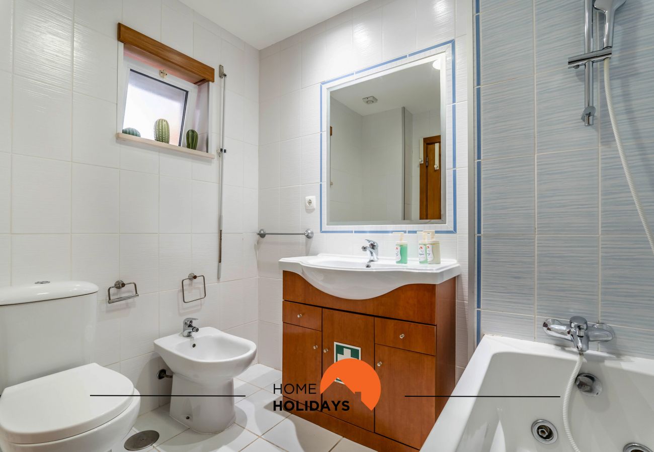 Casa de banho com banheira, lavatório com móvel e espelho