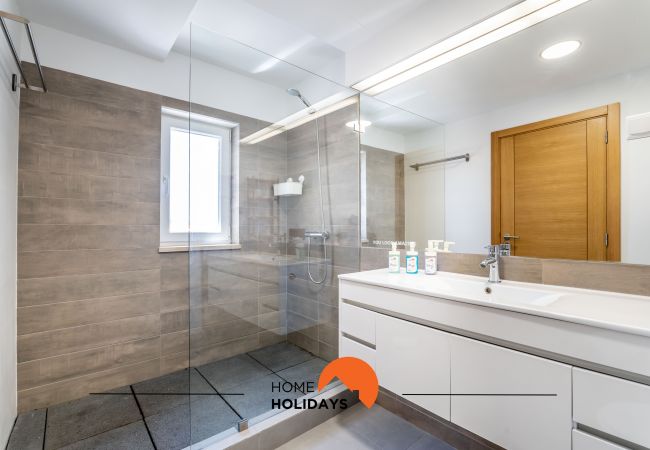 Casa de banho com amplo chuveiro, lavatório com armário e espelho