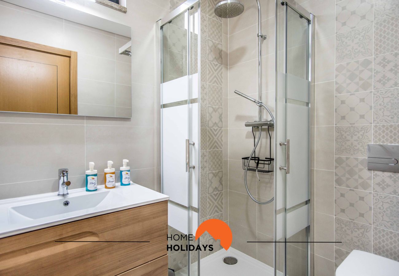 Casa de banho com chuveiro, lavatório com móvel e espelho